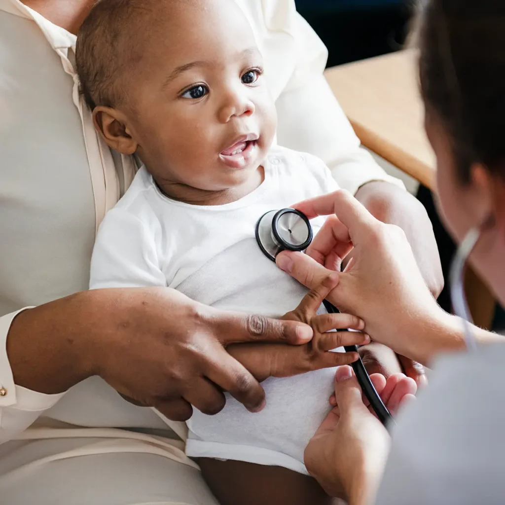 A doctor using a stethoscope to check a baby's heart.